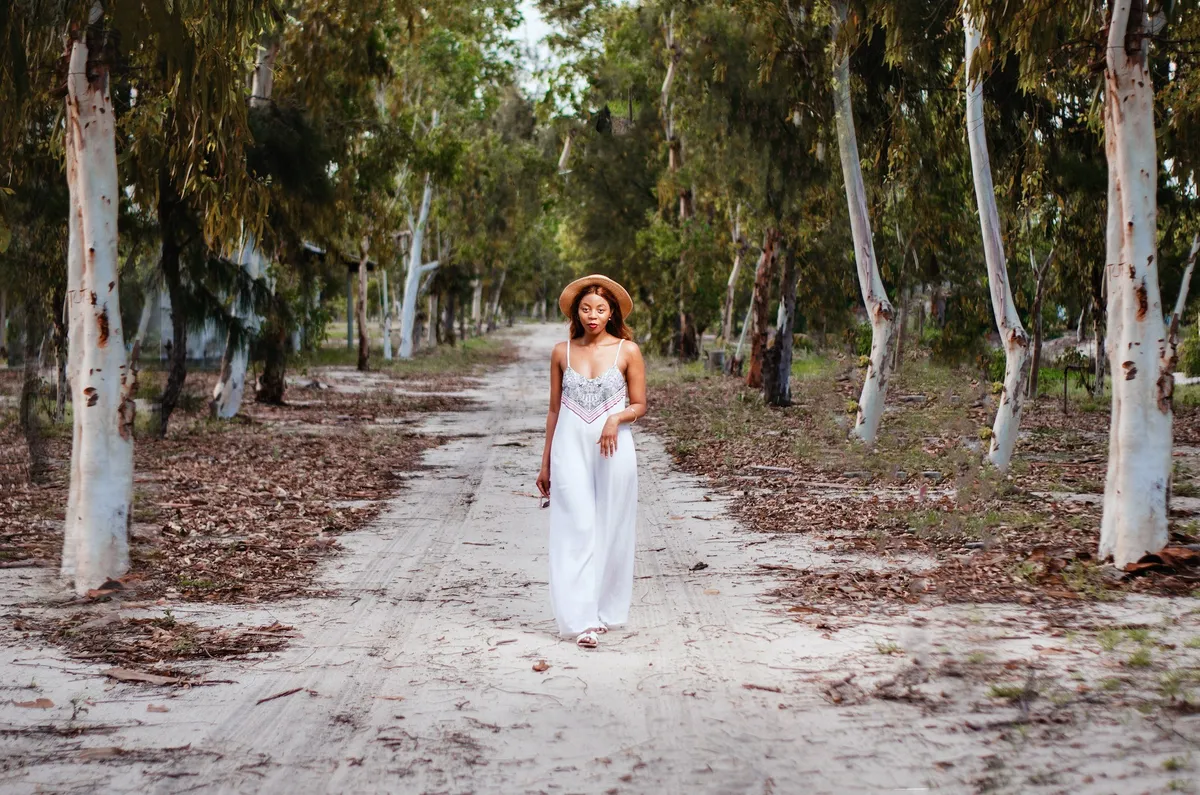 A woman walking a sandy path between eucalyptus trees