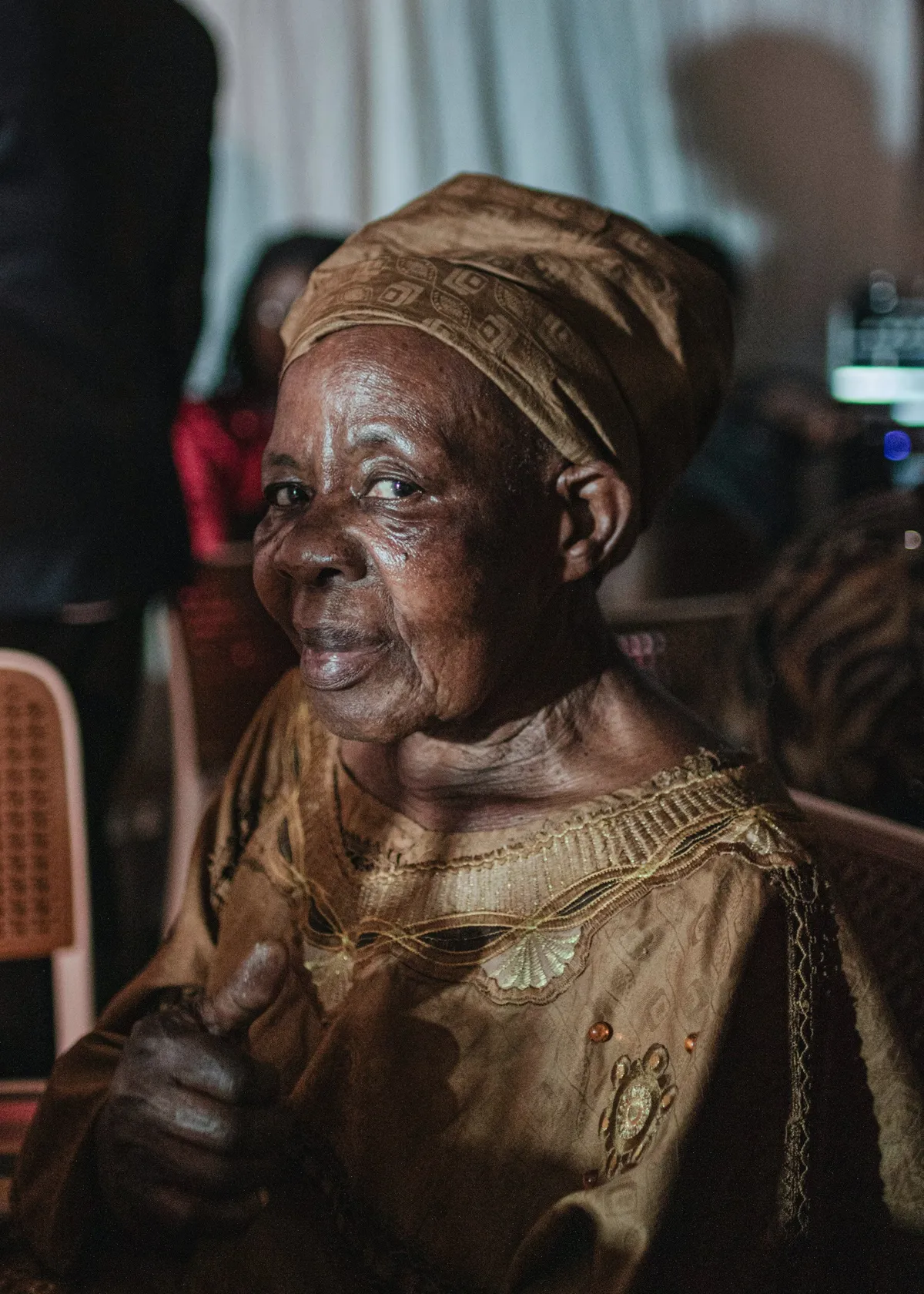 An elder in a headwrap, smiling with quiet confidence